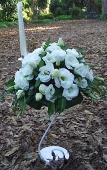 סידור פרחים על סטנד בצבע לבן עם נר